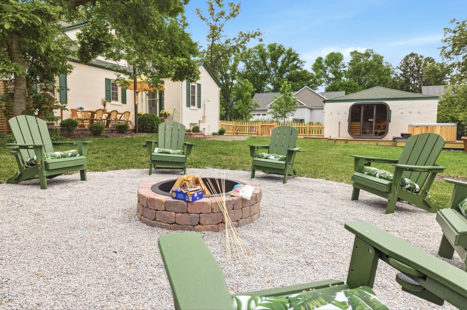 The fire pit ringed by green Adirondack chairs in the fully enclosed yard