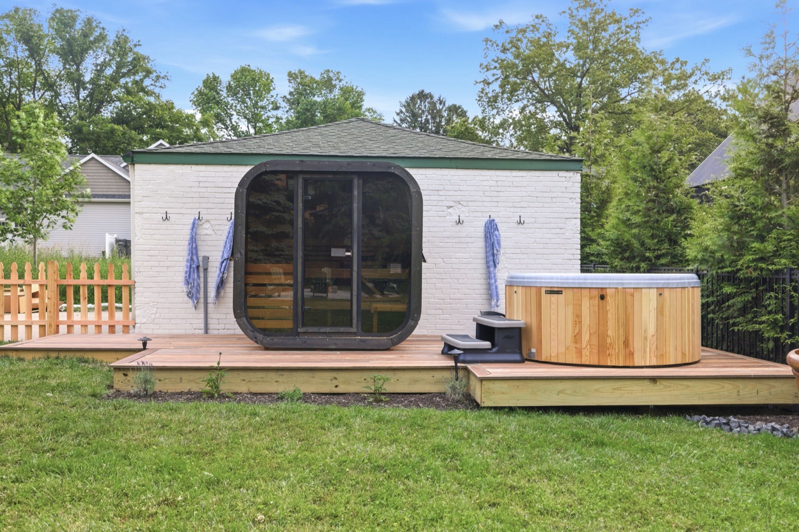 The cedar hot tub beside the outdoor sauna cube on the back deck