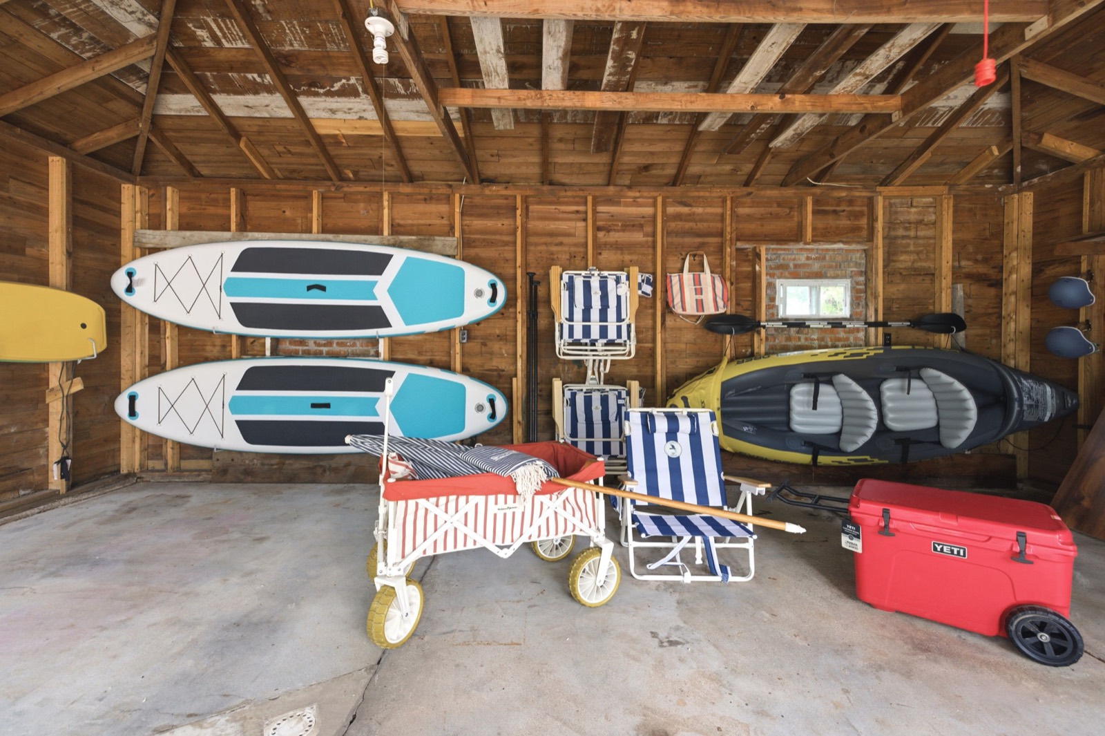 The garage beach kit: paddleboards, beach cart, chairs, and the Yeti cooler ready for the lake