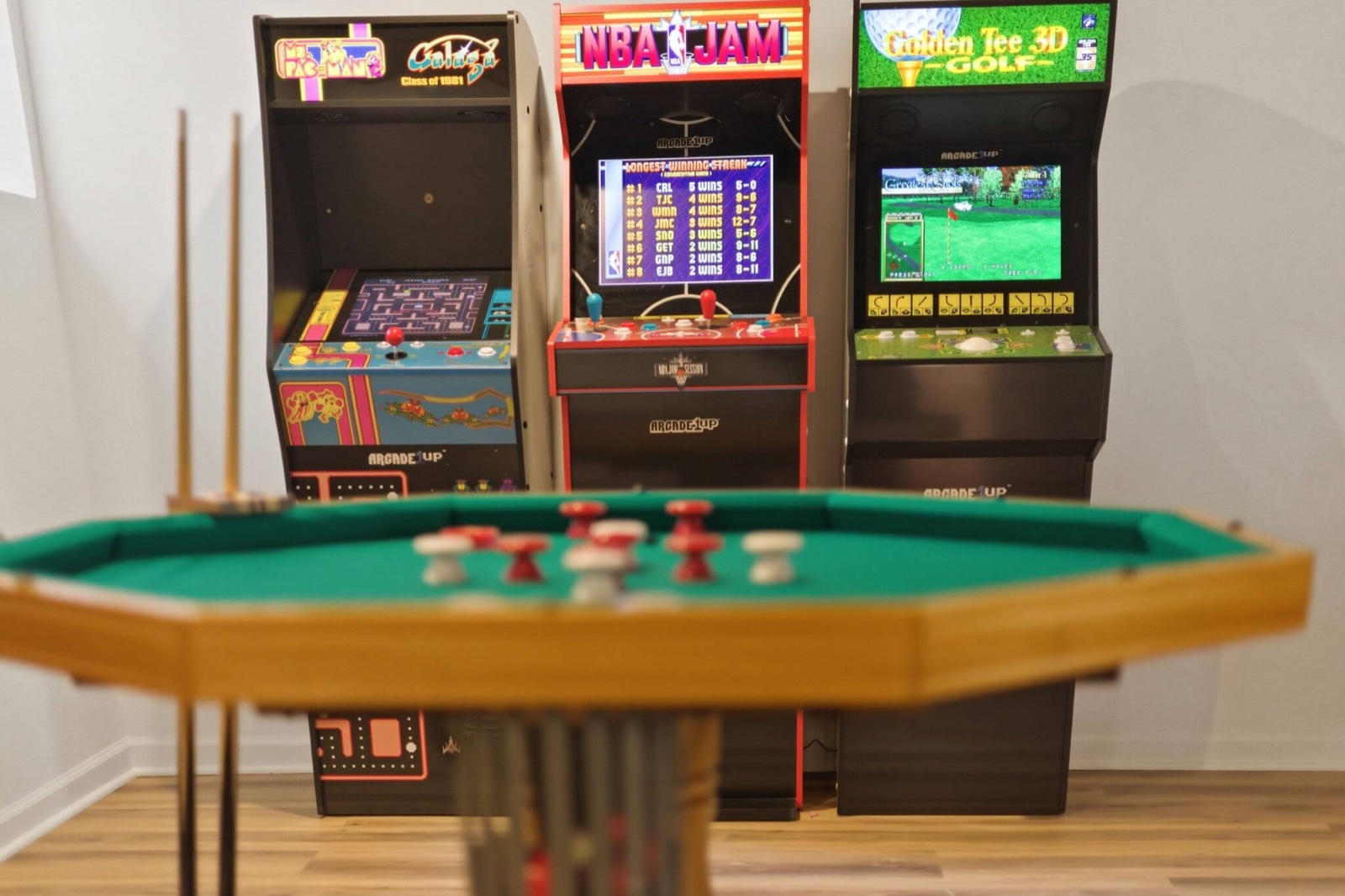 Classic arcade cabinets behind the bumper pool table in the game room