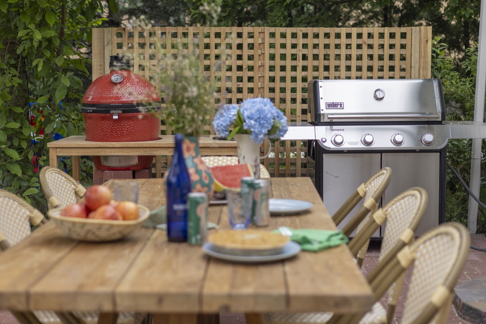 The patio table set for dinner with the Kamado Joe and gas grill behind