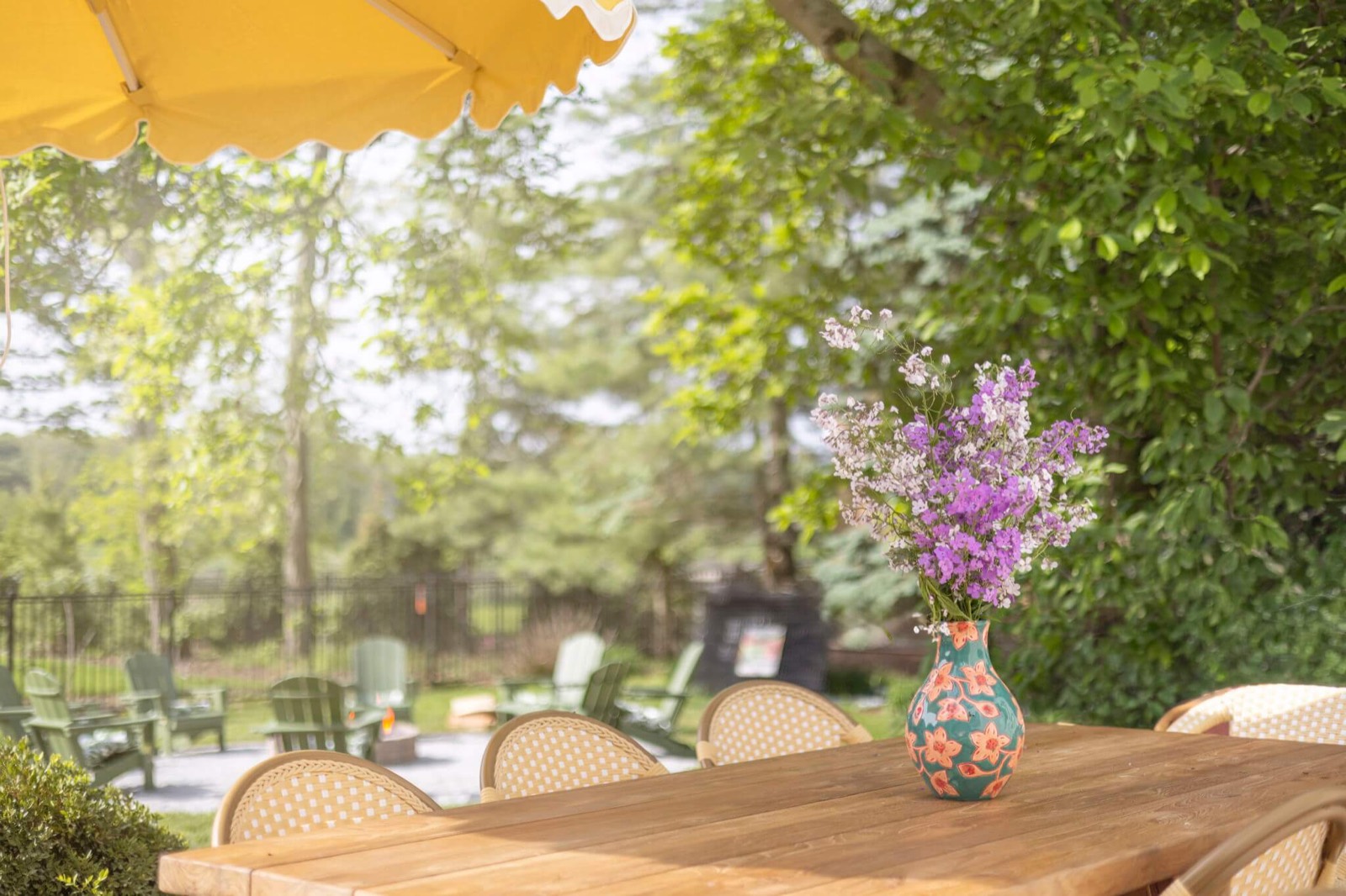 Wildflowers in a painted vase on the outdoor dining table under the yellow umbrella